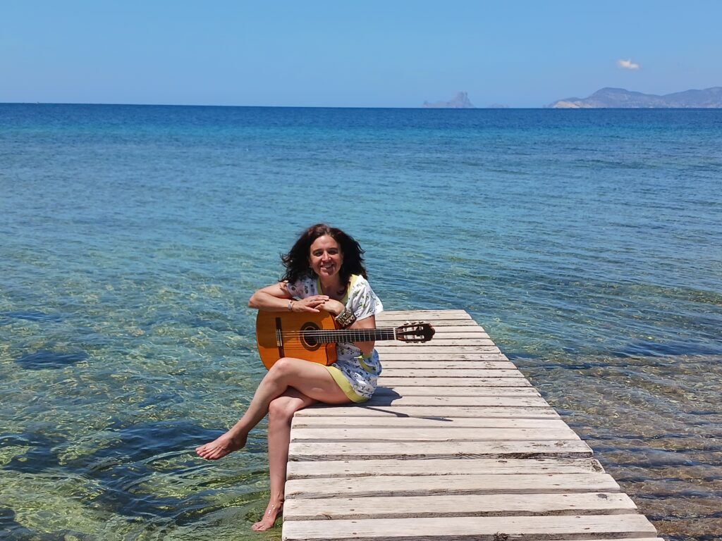 Portrait photo of Roxana Mouriño and her guitar by Formentera's sea