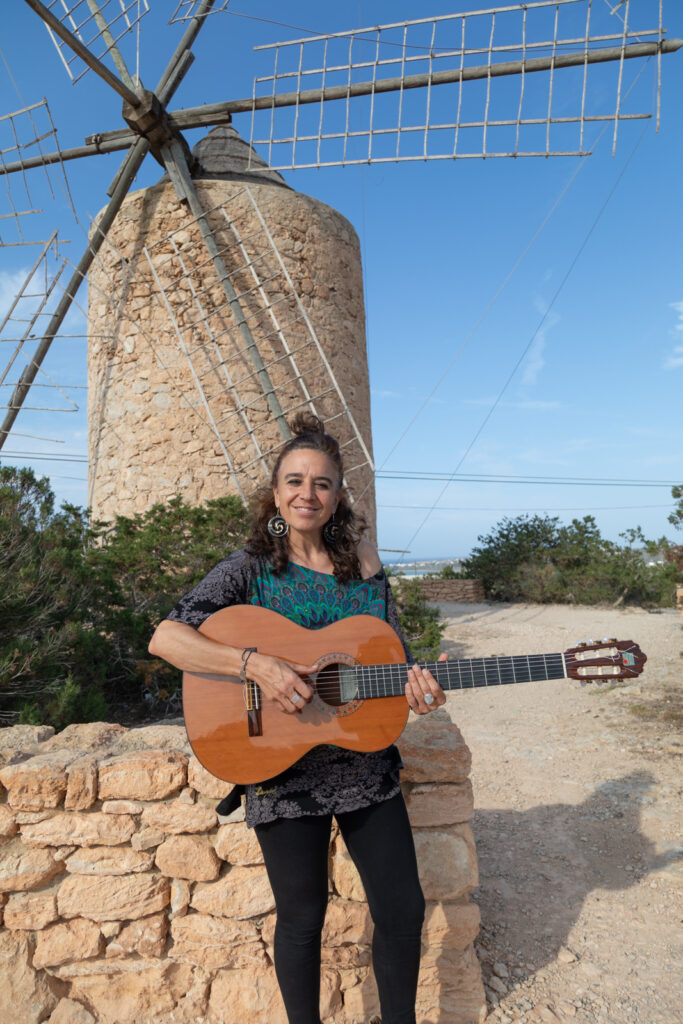 Portrait photo of Roxana Mouriño and her guitar in Formentera's old mill